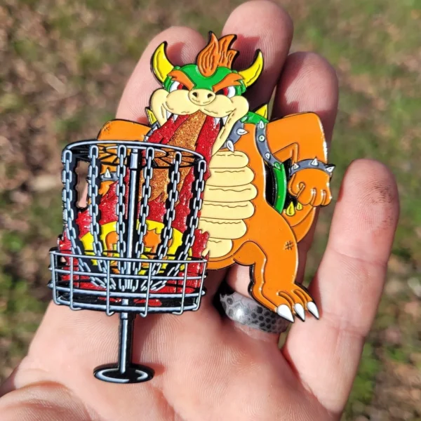A person holding a dragon pin and a frisbee.
