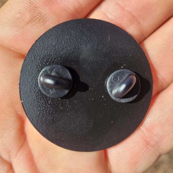 A person holding a black button in their hand.