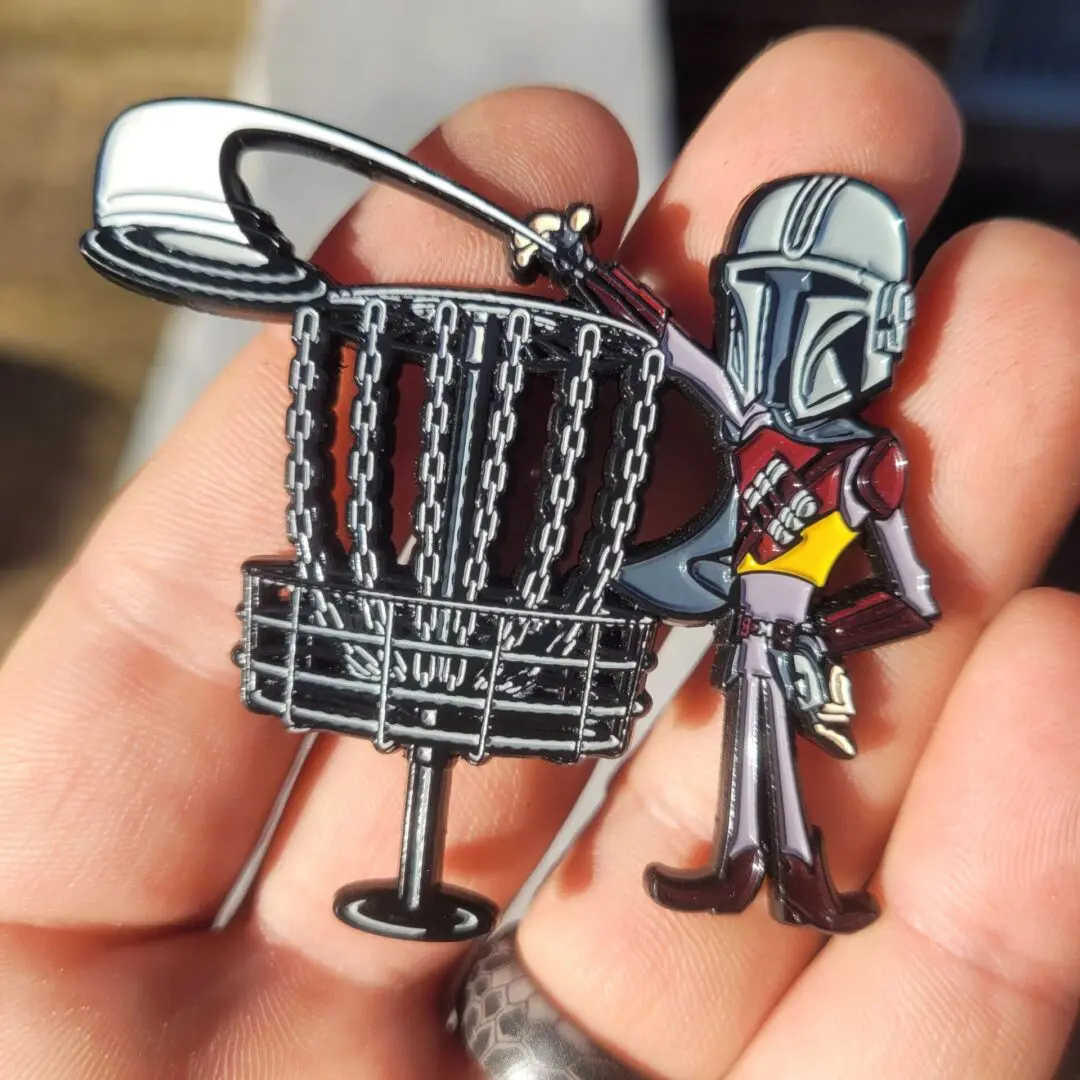 A person holding up a metal pin with a basket in it.