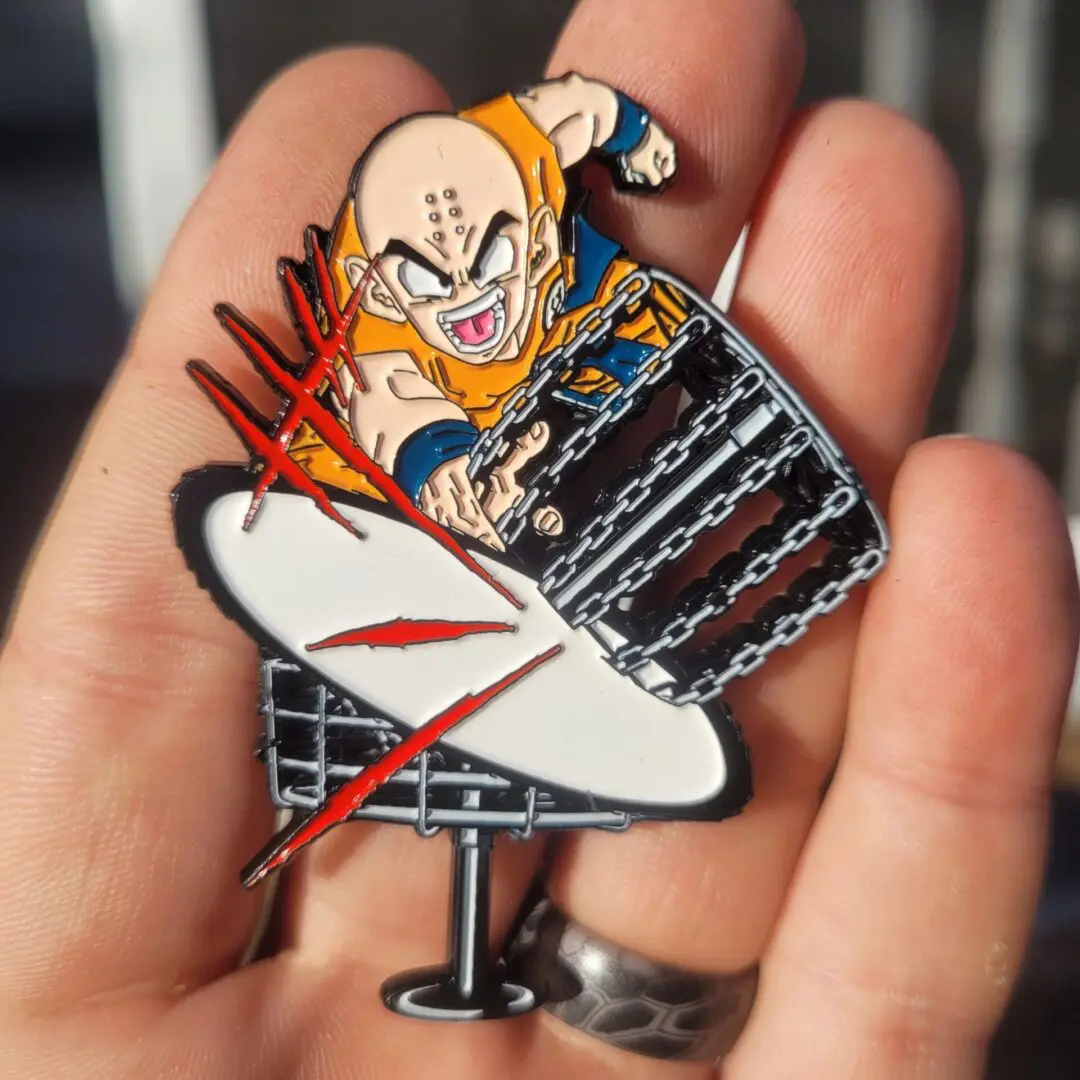 A hand holding up a pin with a dragon ball z character on it.