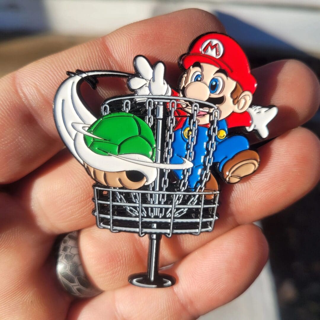 A person holding up a pin with mario in it.