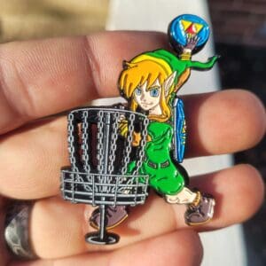A person holding up a pin with a cartoon character on it.