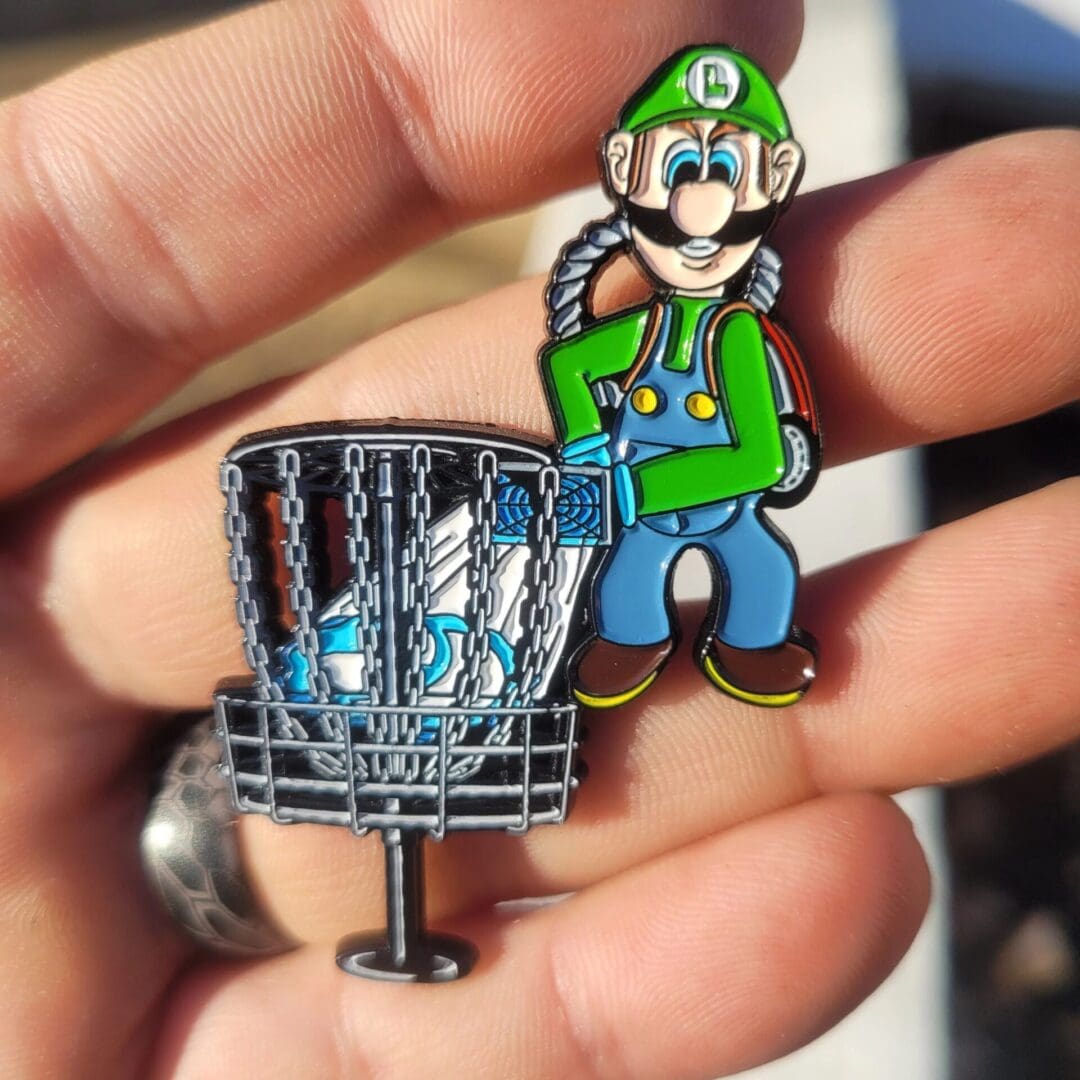 A person holding up a pin with a mario character on it.