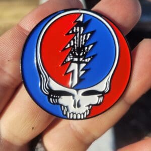 A person holding up a pin with a steal your face on it.