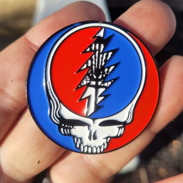 A person holding up a pin with a steal your face on it.