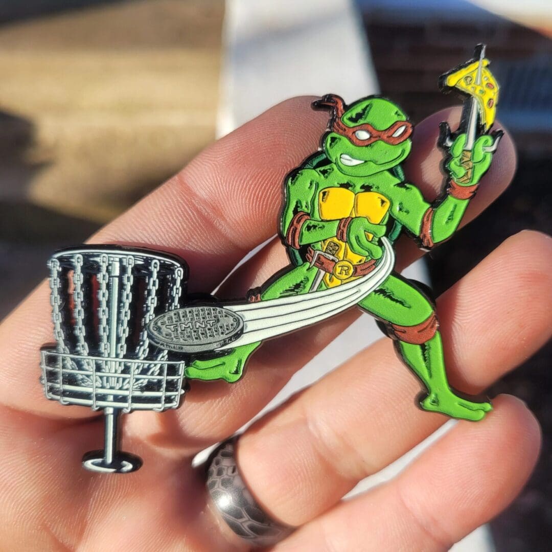 A hand holding a frisbee and a metal figure.