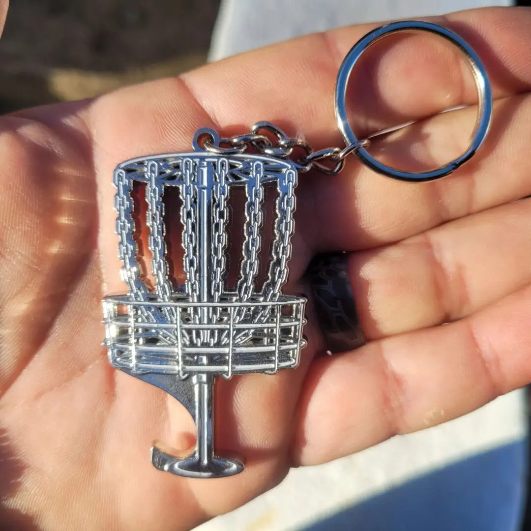 A person holding a keychain with a metal basket.