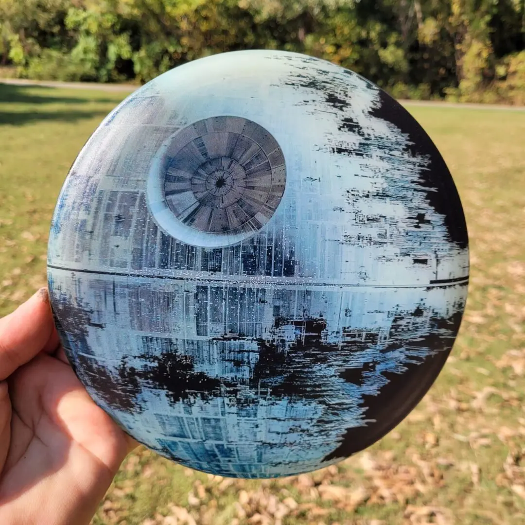 A person holding a frisbee with a picture of the death star.