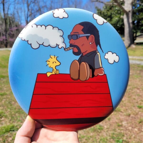 A hand holding up a frisbee with snoop dogg on it.